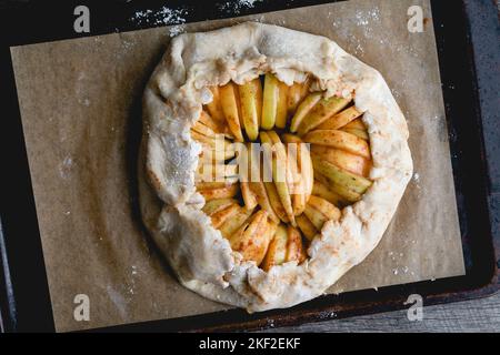 Assembled Unbaked Salted Caramel Apple Galette Viewed from Above: A raw apple galette on a parchment paper lined sheet pan Stock Photo