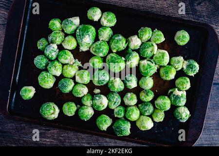 Raw Brussels Sprouts Tossed in Garlic Butter on a Sheet Pan: Brussels sprouts covered in garlic butter and spread on a baking sheet Stock Photo