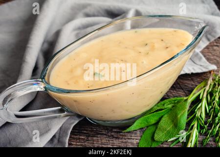 Classic Southern Gravy Made with Fresh Herbs in a Gravy Boat: Homemade gravy in a glass gravy boat with fresh herbs on the side Stock Photo