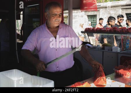 Istanbul, Turkey - October 1 2022: A traditional Turkish street vendor in the tourist district of Sultanahmet sells large watermelons out of a food st Stock Photo