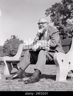 1950s MIDDLE-AGED BUSINESSMAN WITH BRIEFCASE IN LAP SITTING ON PARK BENCH HAND TO CHIN THINKING LOST IN THOUGHT - s11914 HAR001 HARS LIFESTYLE SATISFACTION ELDER COPY SPACE HALF-LENGTH PENSIVE PERSONS THOUGHTFUL MALES CHIN EYEGLASSES EXPRESSIONS MIDDLE-AGED B&W RESTING MIDDLE-AGED MAN LAP DAYDREAMING THOUGHT SUIT AND TIE DREAMS SELLING OLD AGE OLDSTERS CHEERFUL OLDSTER LOW ANGLE REFLECTIVE THINK OPPORTUNITY OCCUPATIONS REFLECTING SMILES ELDERS PONDER PONDERING CONSIDER LOST IN THOUGHT JOYFUL CONTEMPLATIVE MEDITATE MEDITATIVE SALESMEN BLACK AND WHITE CAUCASIAN ETHNICITY CONSIDERING HAR001 Stock Photo