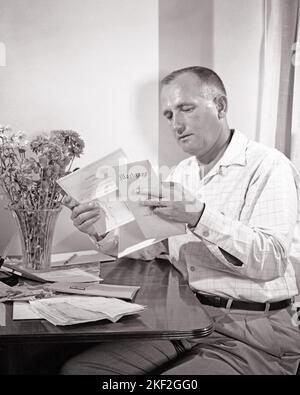 1950s MAN HOMEOWNER SITTING AT TABLE REVIEWING HIS MORTGAGE DOCUMENTS AND OTHER BUDGET PAPERS AND BILLS - s276 HAR001 HARS RESIDENTIAL MALES MORTGAGE BUILDINGS EXPRESSIONS B&W CONCERNED DOCUMENTS HIS AND KNOWLEDGE OPPORTUNITY HOMES BUDGETING REVIEWING HOMEOWNER RESIDENCE MID-ADULT MID-ADULT MAN REFINANCE BLACK AND WHITE CAUCASIAN ETHNICITY HAR001 OLD FASHIONED Stock Photo
