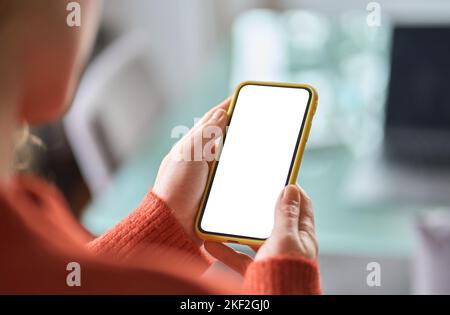Over shoulder view of woman holding smartphone white mock up screen. Stock Photo