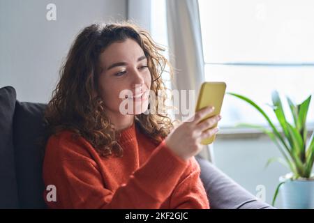 Young pretty woman holding mobile phone using cellphone at home. Stock Photo