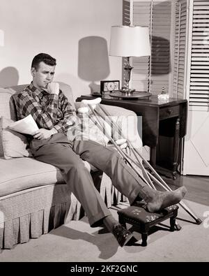 1950s WORRIED MAN HOLDING HANDFUL OF BILLS WHILE SITTING ON LIVING ROOM SOFA WITH CRUTCHES AND HIS INJURED FOOT UP ON A STOOL - s4373 HAR001 HARS ILLNESS HOME LIFE COPY SPACE FULL-LENGTH PERSONS MALES RISK TROUBLED B&W CONCERNED SADNESS HEALTHCARE DISASTER PREVENTION HIGH ANGLE HIS HEALING STRATEGY ACCIDENTAL AND DIAGNOSIS PRIDE HEALTH CARE UP IMPAIRMENT MOOD TREATMENT ACCIDENTS GLUM MISHAP CATASTROPHE HANDFUL MID-ADULT MID-ADULT MAN MISERABLE MISFORTUNE SOLUTIONS YOUNG ADULT MAN BLACK AND WHITE CAUCASIAN ETHNICITY DISEASE HAR001 INVOICES OLD FASHIONED Stock Photo