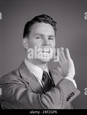 1940s YOUNG MAN WITH AN ANGRY ARROGANT FACIAL EXPRESSION RAISING HIS HAND IN A RUDE DISMISSIVE BACKHANDED GESTURE  - s5471 HAR001 HARS B&W SADNESS EYE CONTACT SUIT AND TIE HEAD AND SHOULDERS DISTRESSED HIS IRATE EXCITEMENT PRIDE GESTURES OCCUPATIONS DISMISSIVE DISPLEASURE HOSTILITY BRASH ANNOYANCE EMOTION EMOTIONAL IMPOLITE IRRITATED RUDE YOUNG ADULT MAN ARROGANT BLACK AND WHITE CAUCASIAN ETHNICITY DISPLEASED HAR001 OLD FASHIONED Stock Photo