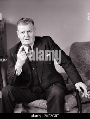 a man wearing a suit smoking a cigarette Stock Photo - Alamy