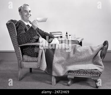 1940s MIDDLE-AGED MAN SITTING IN CHAIR FEET UP ON STOOL HOLDING AN INSURANCE CHECK WEARING ROBE AND PAJAMAS MEDICINE ON TABLE - s9507 HAR001 HARS PAJAMAS AILMENT MIDDLE-AGED B&W RESTING MIDDLE-AGED MAN EYE CONTACT HEALTHCARE SUFFERING HAPPINESS WELLNESS PREVENTION CHEERFUL HEALING AND DIAGNOSIS RECOVERY RELAXED HEALTH CARE UP IMPAIRMENT SMILES TREATMENT RECOVERING FOOTSTOOL JOYFUL STYLISH POOR HEALTH AILING RELAXATION REST SOLUTIONS BLACK AND WHITE CAUCASIAN ETHNICITY DISEASE HAR001 OLD FASHIONED Stock Photo