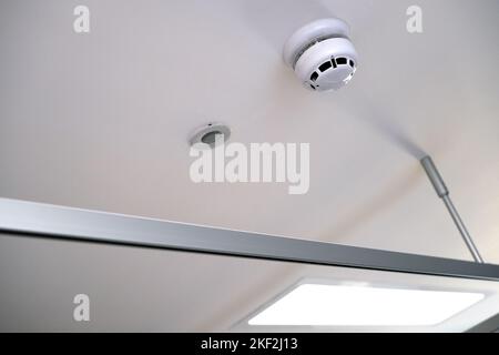 Ceiling fittings and fixtures in modern clinical setting. Smoke or carbon monoxide detector and alarm and emergency lighting LED. Metal and plastic Stock Photo
