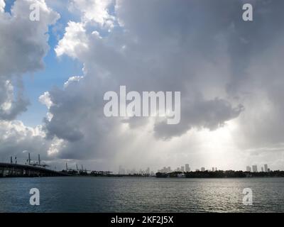 Rainstorm clouds over Downtown Miami. Sun bursting through clouds and pouring onto City skyline. Blue sky peeking through. View from South Beach. Stock Photo