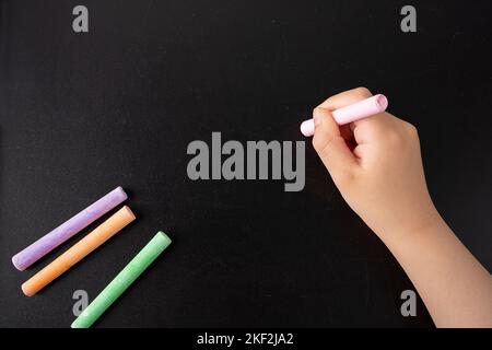 Closeup of a hand of child with chalk writing on a blackboard Stock Photo