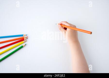 High angle shot of child hand draws a orange pencil Stock Photo