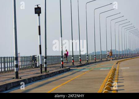 Man exercising on street early morning while two people are jogging nearby, Nakhon Phanom, Thailand. Stock Photo