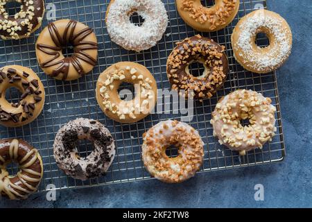 An above view of a cooling rack with glazed donuts and assorted toppings. Stock Photo