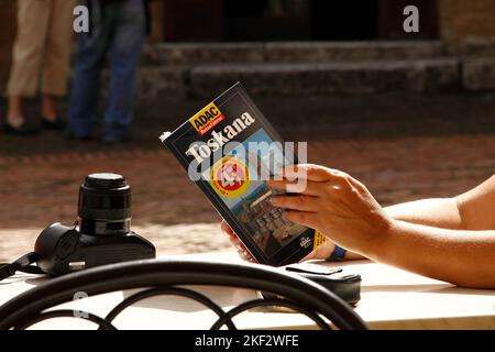 Hands of a female tourist holding German ADAC Toskana travel guide, Tuscany, Italy Stock Photo