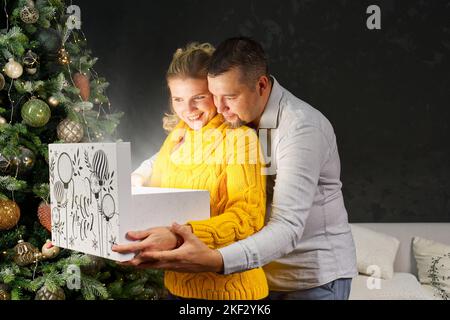 Man giving a Christmas present to his girlfriend. Opening gift box at christmas time. Christmas wonder concept Stock Photo