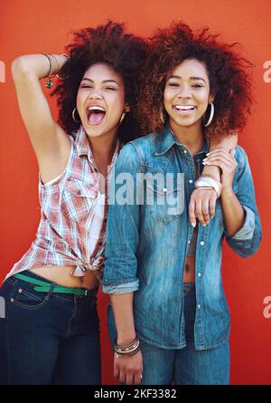 My bestie is crazy cool. two young friends posing against a red background. Stock Photo