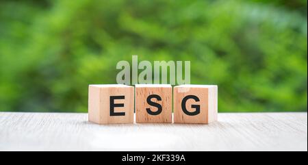 ESG, letters on wood block cube with green nature background. Environmental, social and governance concept. Stock Photo