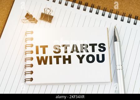 Economy and business concept. On the table there is a pen, clamps and a notebook with the inscription - IT STARTS WITH YOU Stock Photo