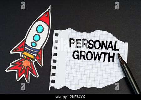 Business and finance concept. On a black background, a rocket, a marker and paper with the inscription - PERSONAL GROWTH Stock Photo
