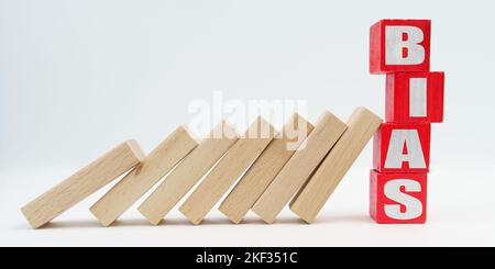 Business and economy concept. On a white background, wooden dice fell like dominoes, the fall was stopped by cubes with the inscription - BIAS Stock Photo