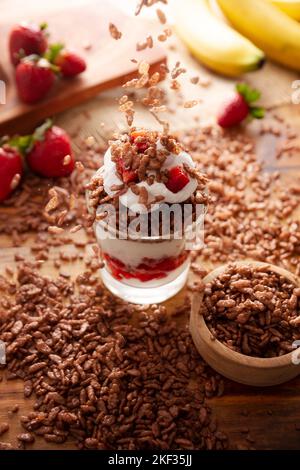 Healthy breakfast of Greek yogurt with fresh fruits and chocolate flavored puffed rice falling. Stock Photo