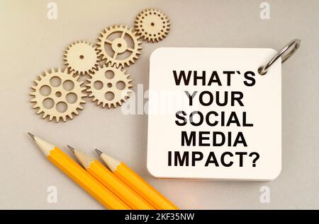 Business and finance concept. On the table are gears, pencils and a notebook with the inscription - What is Your Social Media Impact Stock Photo