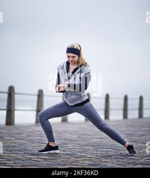 Training hard for that upcoming race. a young woman checking her watch while exercising outdoors. Stock Photo