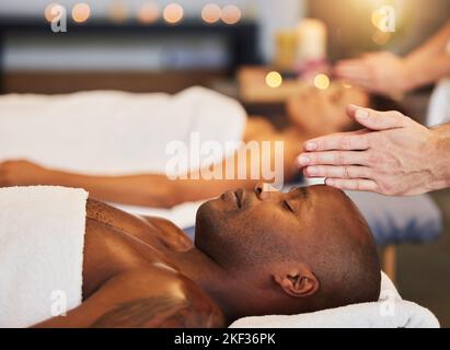 Hands, massage and relax with a black man customer in a spa for physical therapy or rest in a resort. Luxury, wellness and zen with a male client Stock Photo