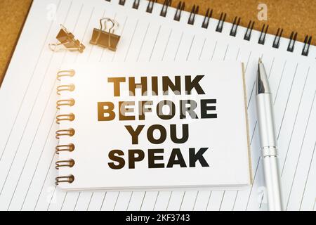 Economy and business concept. On the table there is a pen, clamps and a notebook with the inscription - THINK BEFORE YOU SPEAK Stock Photo