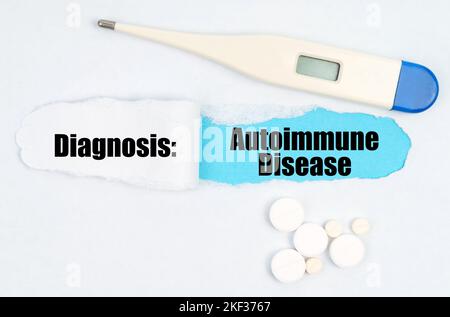 Medical diagnosis. A gap is made in the middle of the white sheet, inside of which there is an inscription - Autoimmune Disease on a blue background. Stock Photo