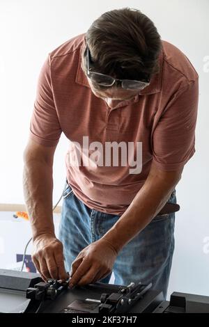 A vertical shot of a handyman using a screwdriver to fix the TV Stock Photo