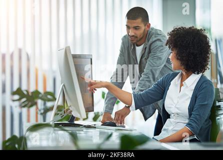 Lets see if this will work...designers talking together at a workstation in an office. Stock Photo