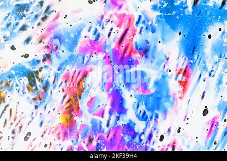 A vibrant chaotic abstract blend of blue, pink, purple and white food dye colours on a thin sheet of slightly crumpled up plastic on a light-box Stock Photo