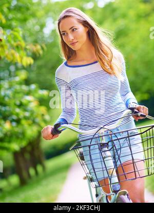 All she needs is a bike and the great outdoors. a young woman cycling in the park. Stock Photo