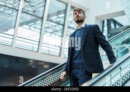 passenger with luggage going up the escalator at the airport . Stock Photo