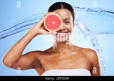 Black woman, grapefruit or smile with water splash for health skincare, wellness or nutrition against a blue studio background. Portrait of happy Stock Photo