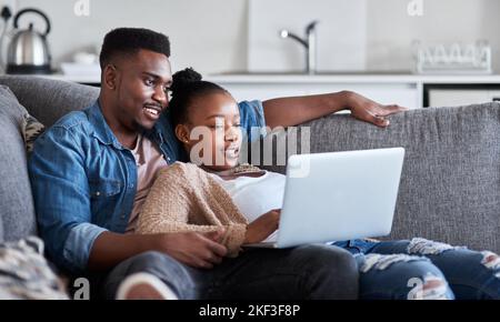 Black couple, laptop and living room sofa to relax while streaming movies, video or film with 5g network connection or home wifi. Man and woman on Stock Photo