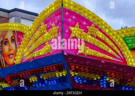 Detail of bright neon lights at outdoor fair ride with female illustration and golden shooting stars. Stock Photo