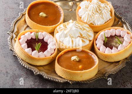 pastry dessert sweet tartlets or cake with cream, curd,  nuts and chocolate close-up on a plate on the table. Horizontal Stock Photo