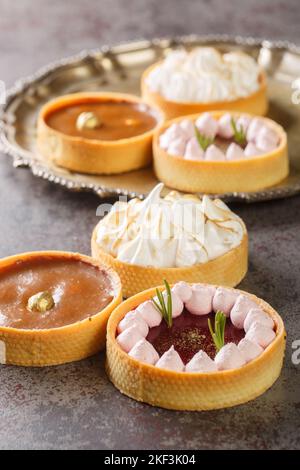 Festive mix tartlets with lemon curd, raspberry curd, nuts and chocolate close-up on the table. Vertical Stock Photo