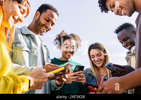 Young group of happy friends using smart mobile phone together outdoors Stock Photo
