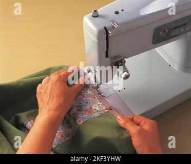 Fastening a piece of fabric tape to the patchwork Stock Photo