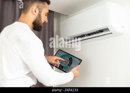 Young Technician using digital tablet and pen checking air conditioner in house room. Air Conditioning system installation and repairing concept Stock Photo