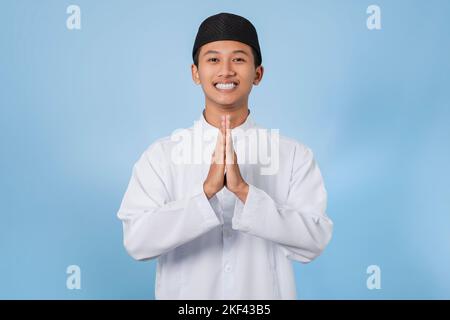 Smiling Asian muslim man happy celebrating Eid Al-Fitr isolated white background. Celebrate Ramadan Holy month in Islam Stock Photo