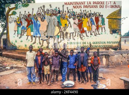 Burkina Faso, Ouagadougou. Children in front of a billboard promoting democracy. Stock Photo