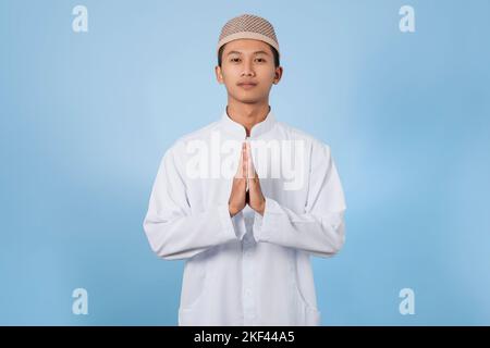 Smiling Asian muslim man happy celebrating Eid Al-Fitr isolated white background. Celebrate Ramadan Holy month in Islam Stock Photo
