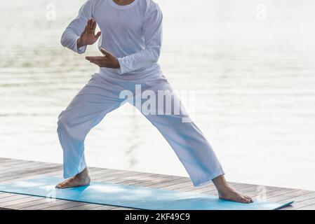 Young man practicing traditional Tai Chi Chuan, Tai Ji  and Qi gong in the park for healthy, traditional chinese martial arts concept on natural backg Stock Photo