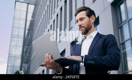 Successful businessman developer creator typing on laptop creates new startup business plan concentrated man working outdoors using computer Stock Photo