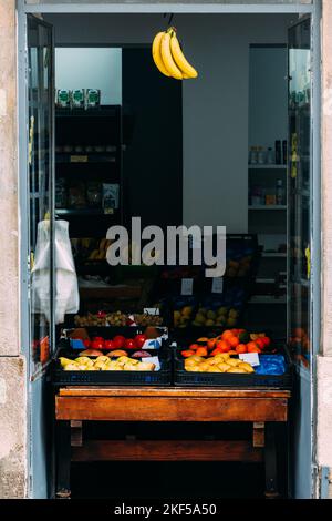 Entrance to a shop selling fresh fruit with bananas hanging from the doorway - captured in Lisbon, Portugal Stock Photo